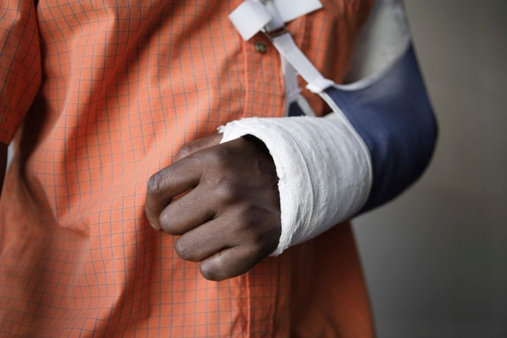 Close-up photo of a persons arm bandaged and in a sling. 
